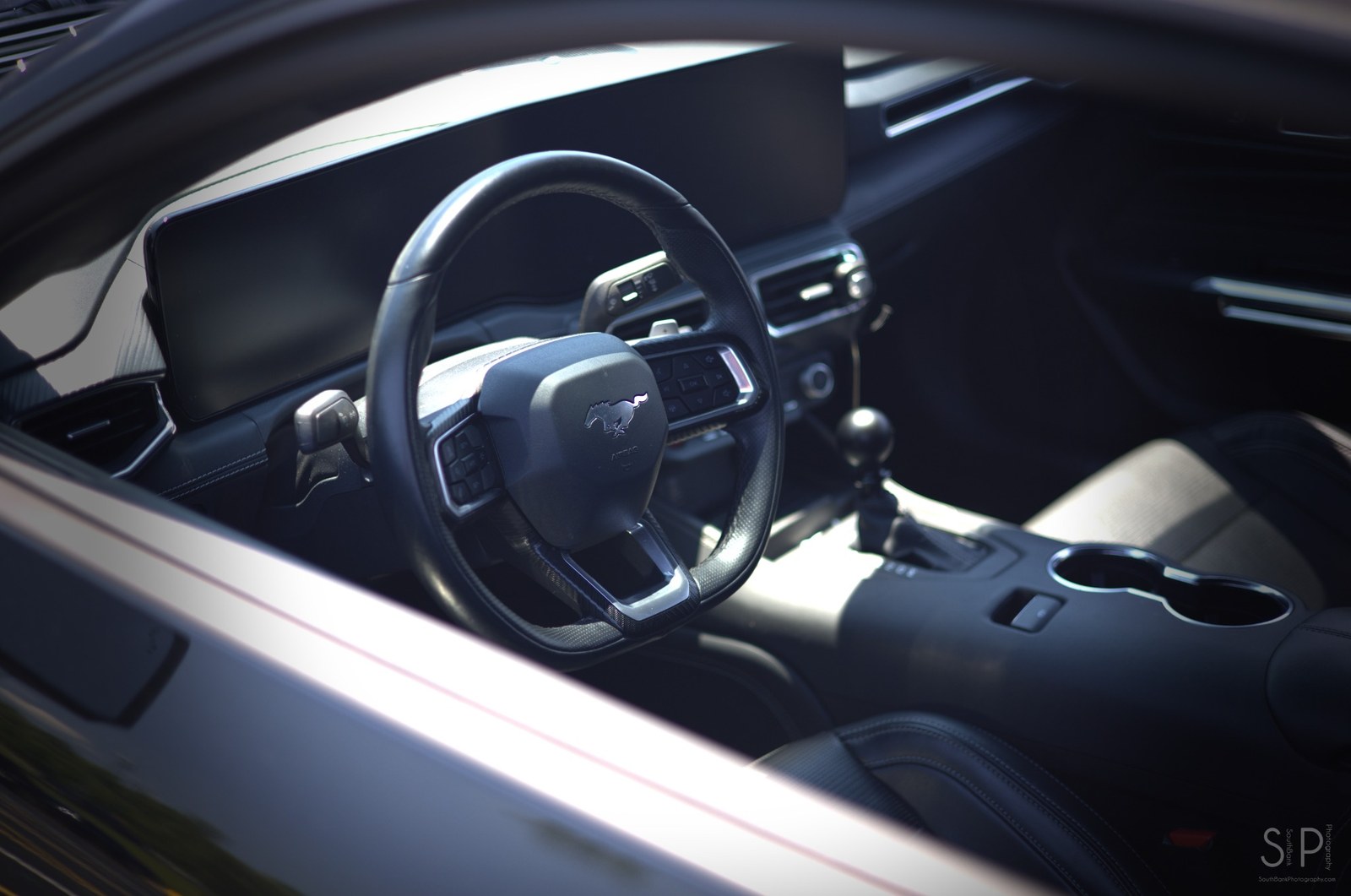 Photo of a modern Mustang interior with steering wheel and console.